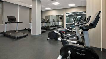 A gym with treadmills, stationary bikes, and a mirrored wall.