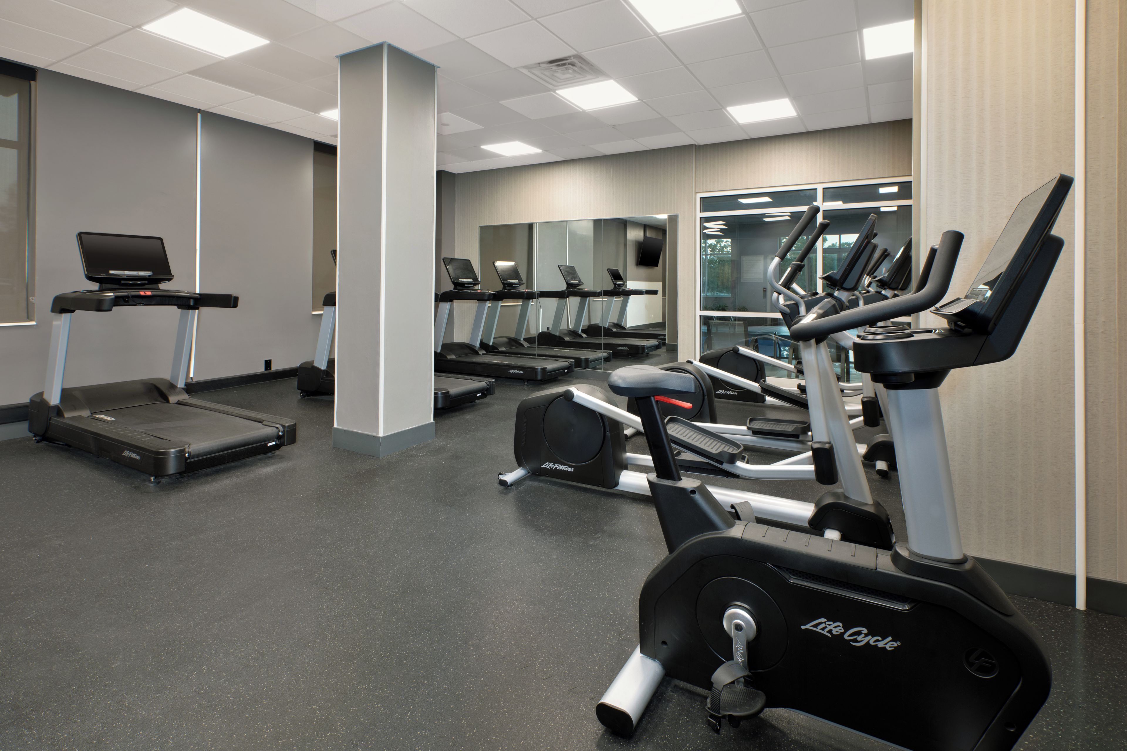 A gym with treadmills, stationary bikes, and a laptop on a treadmill.