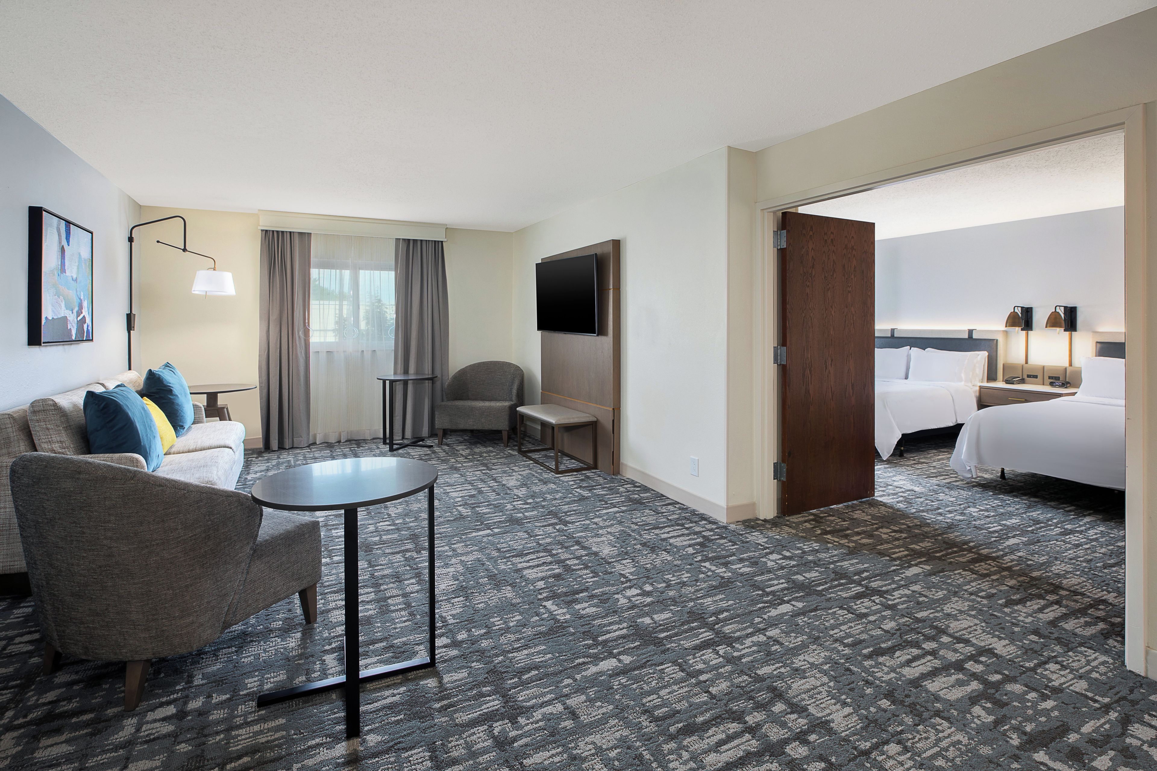 Une chambre d’hôtel avec un canapé, un fauteuil, une petite table et un lit.