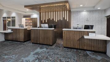 A reception area with wooden reception desks, a sign indicating 'The Marketplace', and a patterned carpet.
