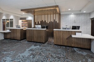 Un área de recepción con mostradores de madera, un cartel que indica 'The Marketplace' y una alfombra estampada.