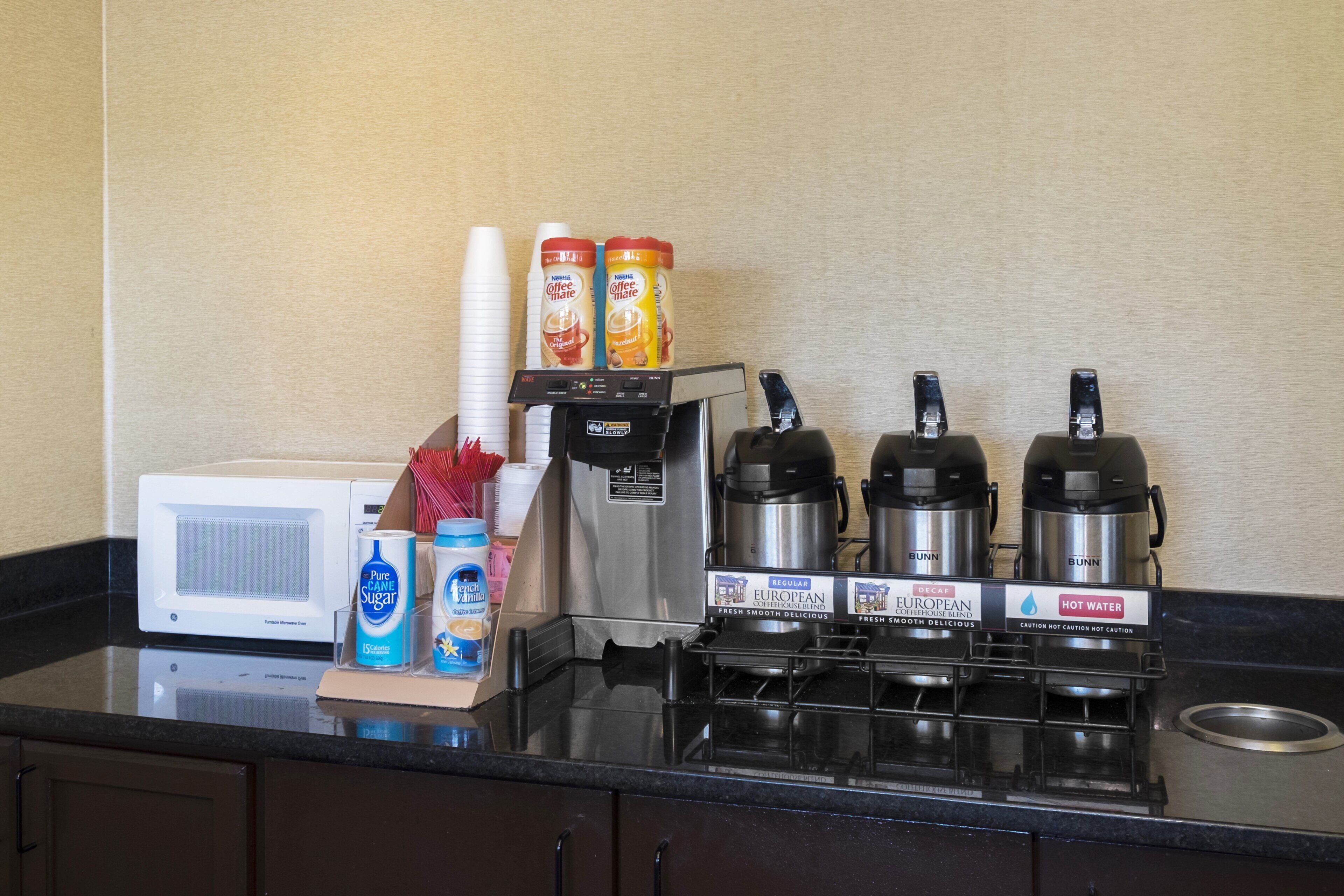 Una kitchenette equipada con microondas, cafetera y cafeteras.