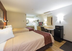 A hotel room with two beds, a desk, a mirror, a television, and a refrigerator. - Red Roof Inn Cincinnati - Sharonville (Sharonville)