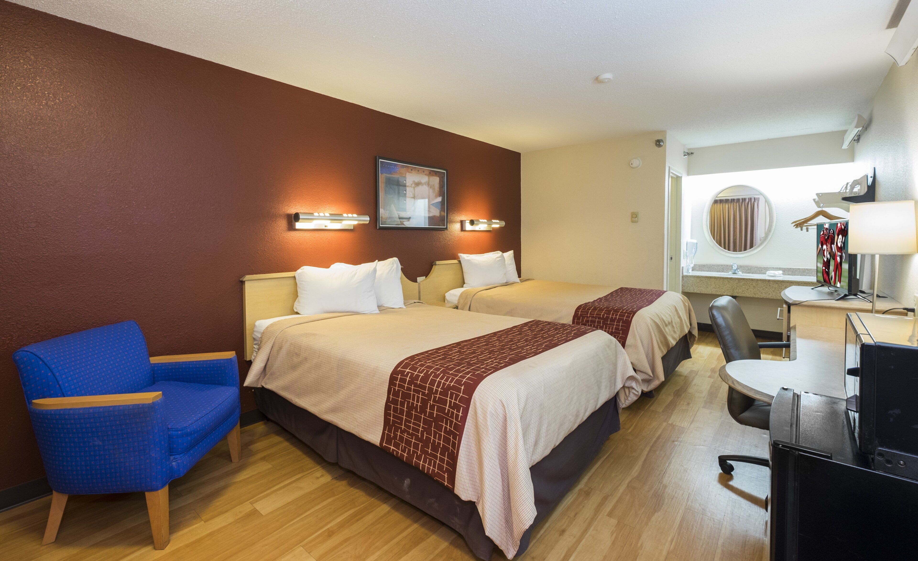Une chambre d’hôtel avec deux lits, un bureau, une chaise et une fenêtre.