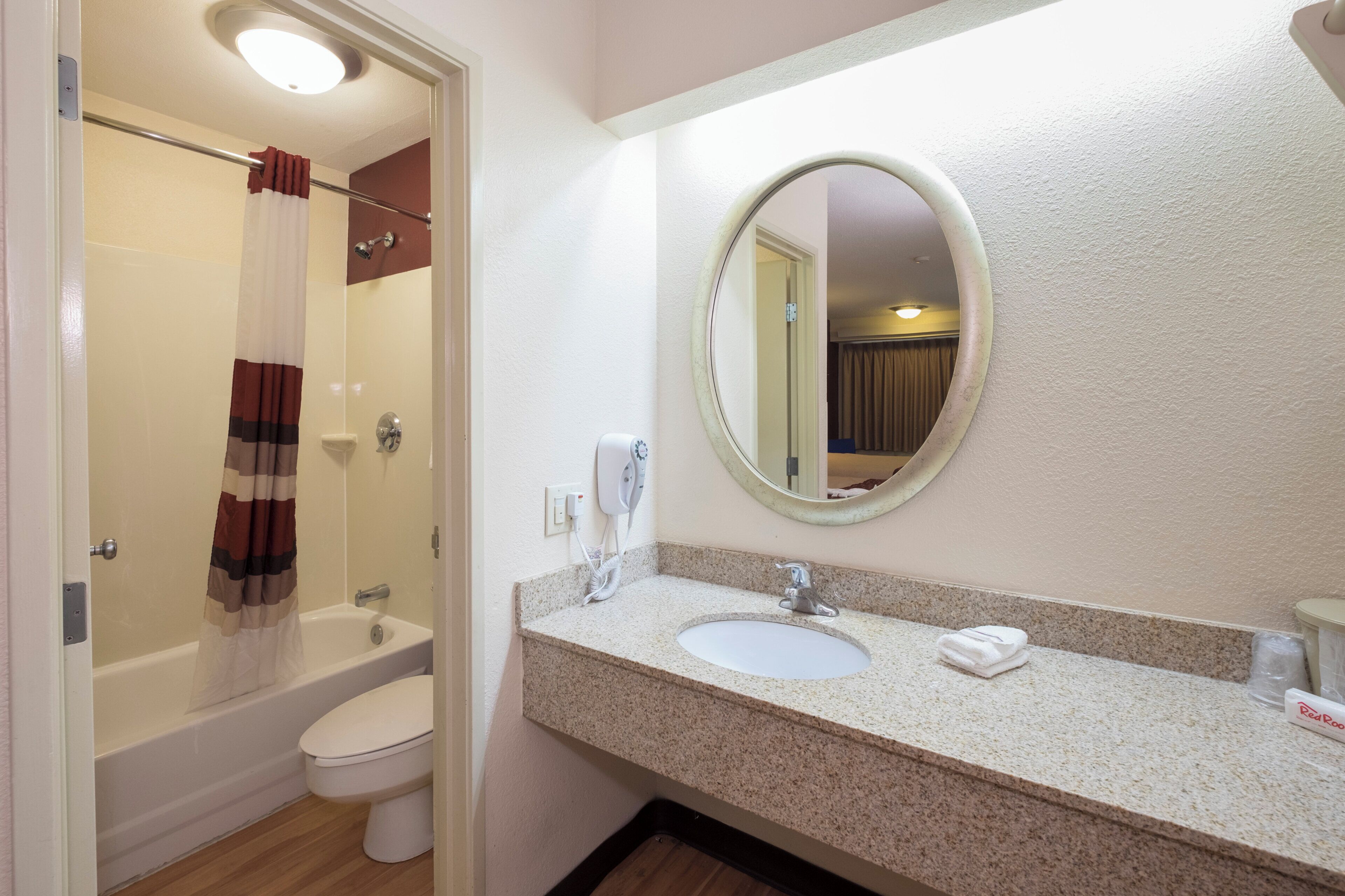 Un baño con ducha, inodoro, lavamanos y espejo.