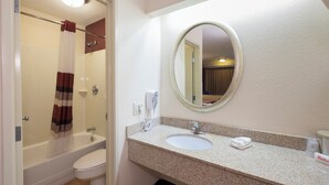 Un baño con ducha, inodoro, lavamanos y espejo.