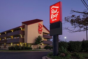 A Red Roof Inn with a modern design, featuring a prominent red and white sign, multiple balconies, and a well-lit entrance. - Red Roof Inn Cincinnati - Sharonville (Sharonville)