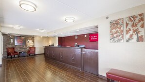 Zona de recepción de un hotel con piso de madera, mostrador de recepción y un letrero que indica Wi-Fi gratuito.