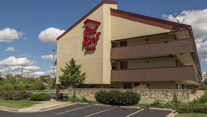 Un hotel Red Roof Inn con techo plano, fachada de piedra y estacionamiento.