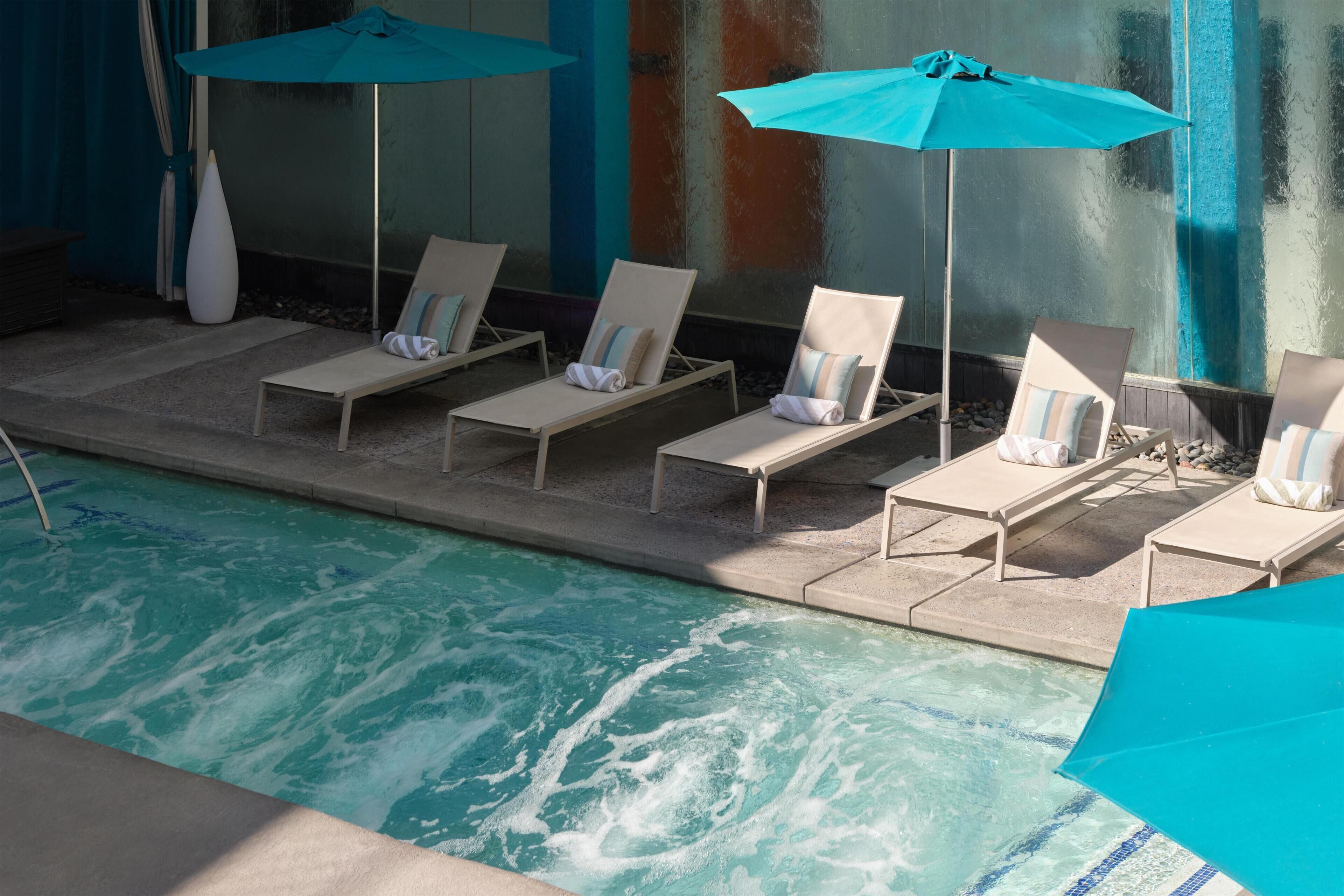 Un espace aménagé au bord de la piscine, avec des chaises longues et des parasols.