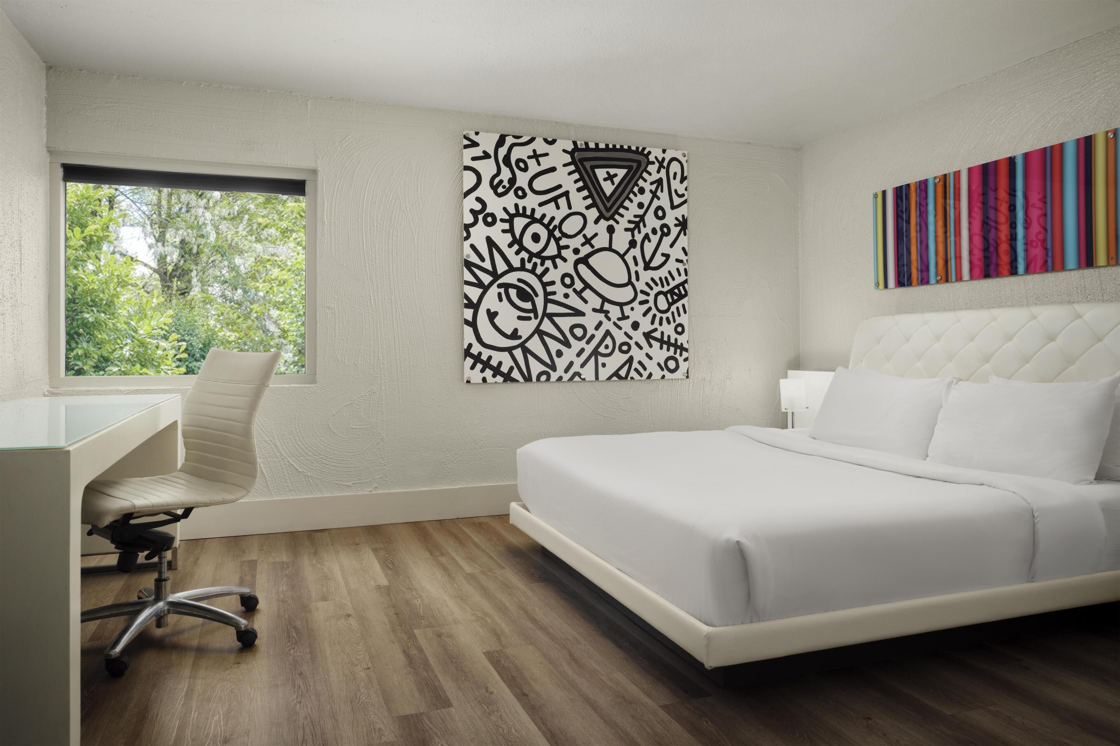A modern bedroom with a bed, a desk, and a window.