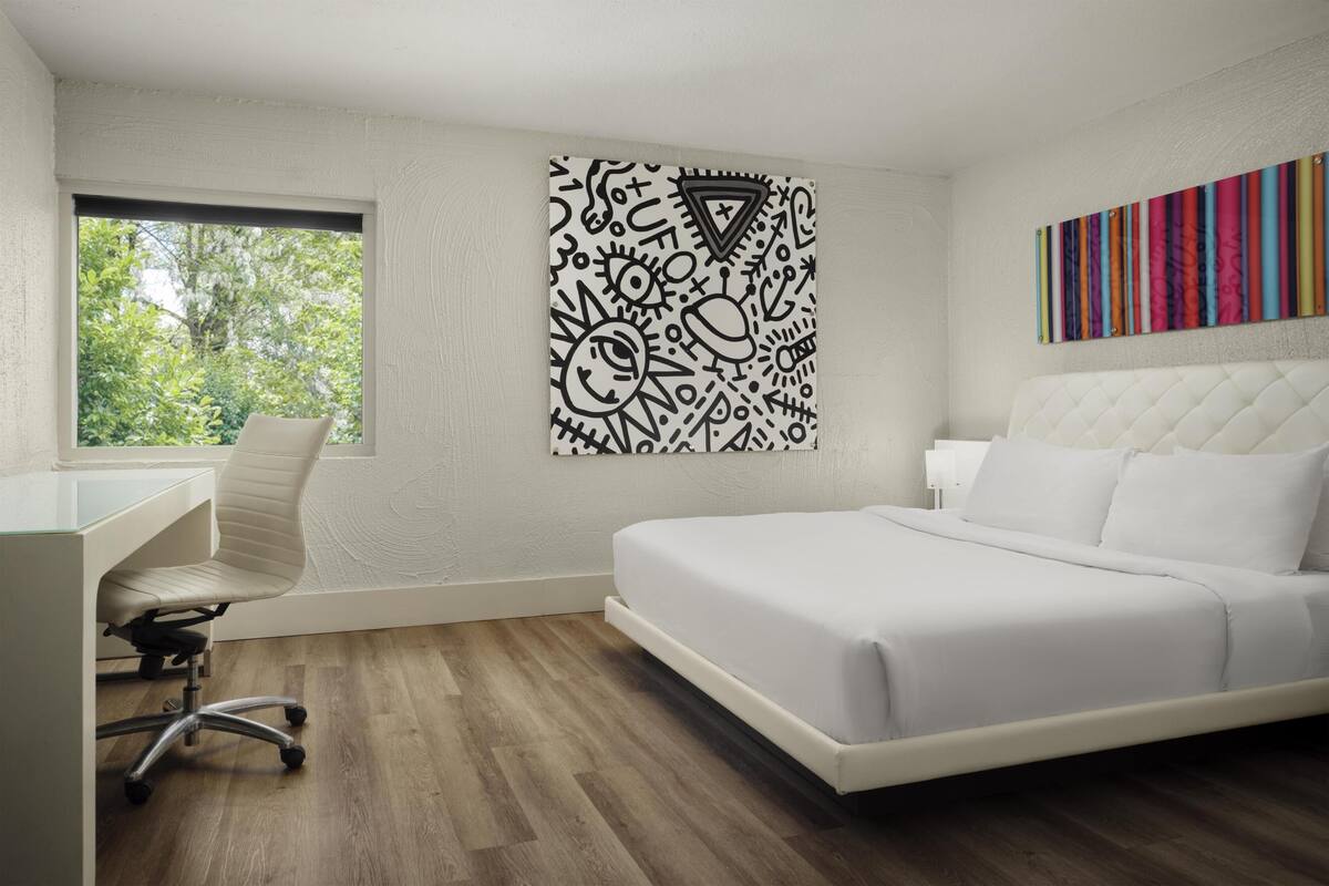 A modern bedroom with a bed, a desk, and a window.