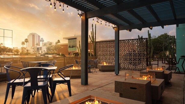 An outdoor seating area with fire pits, chairs, and a patterned wall.