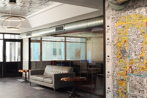 A modern lobby with a leather sofa, a wooden table, and a large wall with doodle-style artwork. - The Clarendon Hotel & Spa, BW Signature Collection (Phoenix)