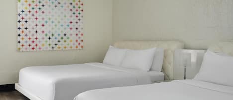 A hotel room with two beds, a large colorful geometric wall art, and a white headboard.
