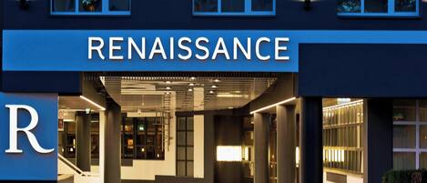 Un edificio moderno con un llamativo letrero 'RENAISSANCE', que presenta un diseño limpio y contemporáneo con grandes ventanales y una entrada bien iluminada.