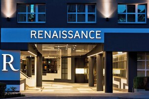 Um edifício moderno com um letreiro chamativo 'RENAISSANCE', apresentando um design limpo e contemporâneo, com grandes janelas e uma entrada bem iluminada.