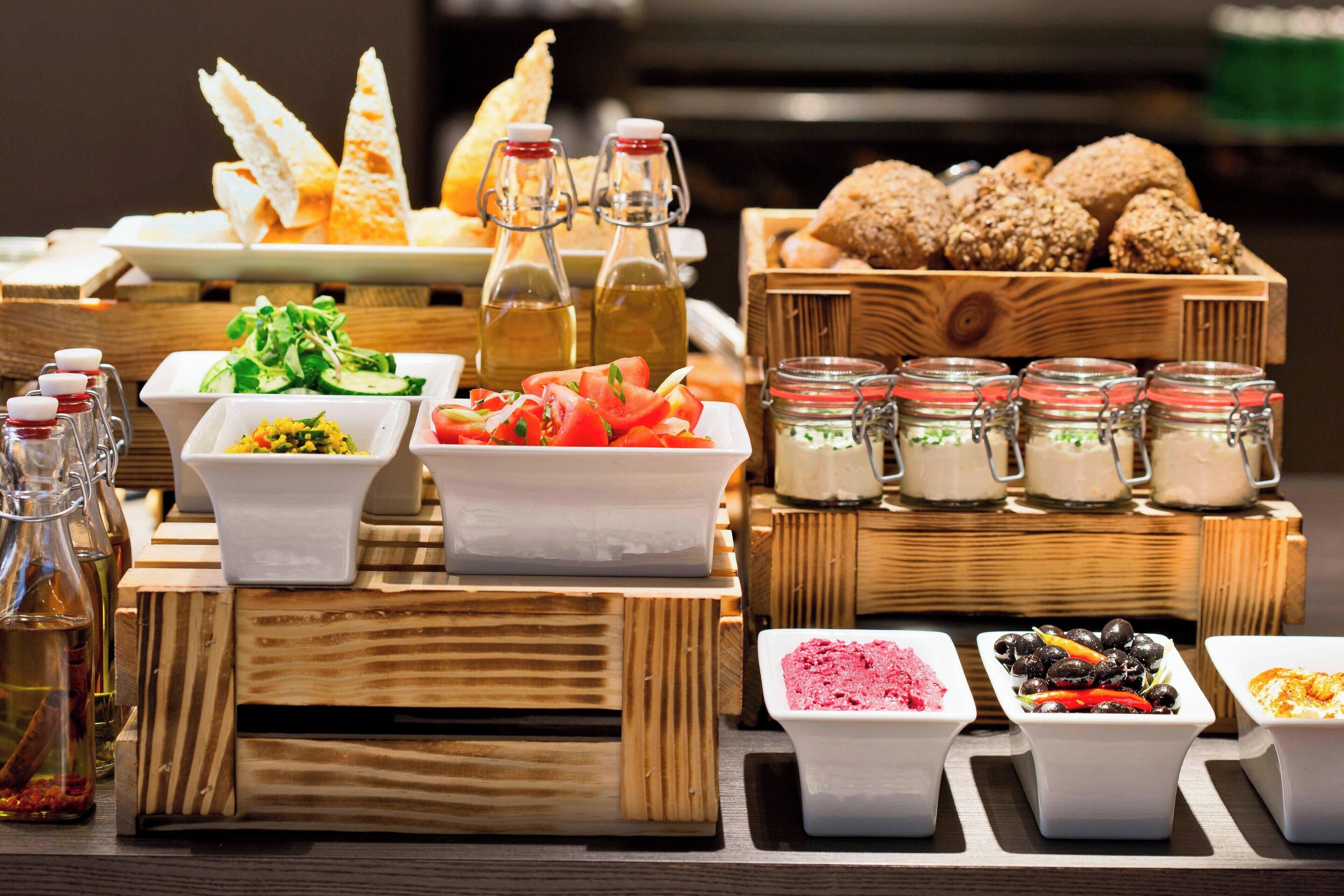 A buffet with various food items, including salads, bread, and condiments.