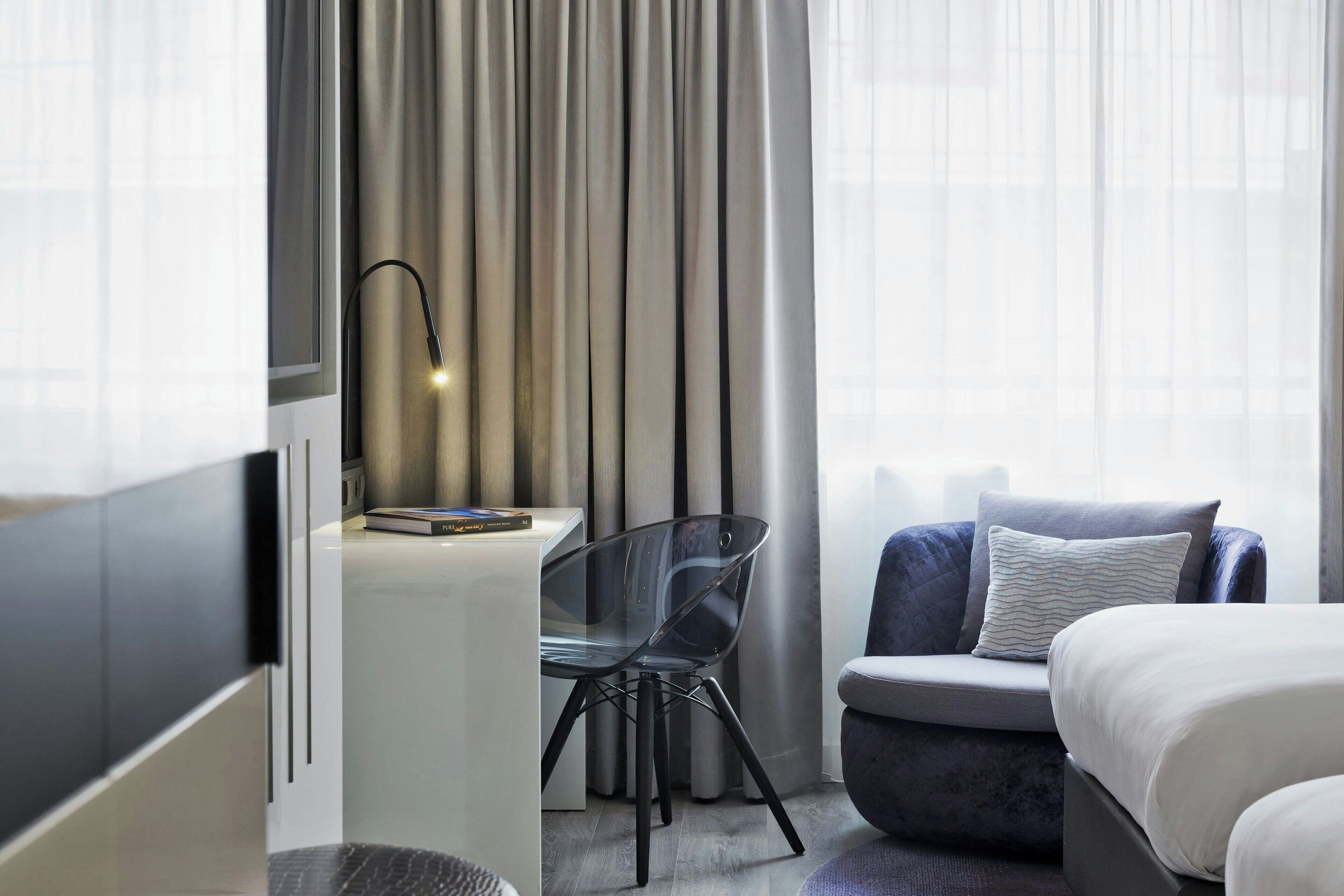 Een hotelkamer met een bed, een bureau, een stoel en een televisie.
