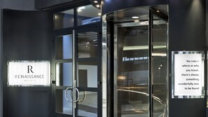 A hotel entrance with a revolving door, a glass door, and a sign that reads "Renaissance Wien Hotel".