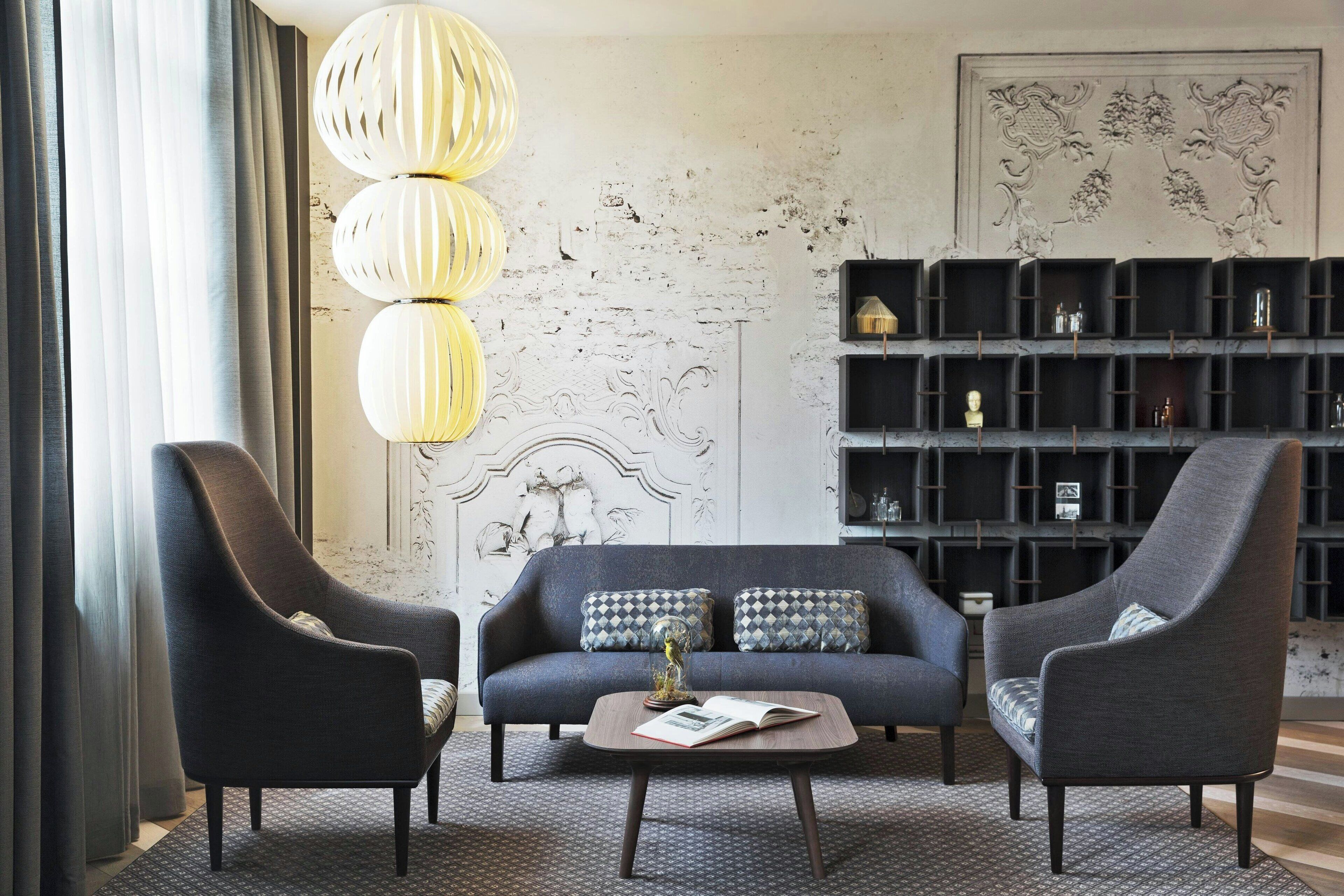 A modern living room with a sofa, two armchairs, a coffee table, and a bookshelf.