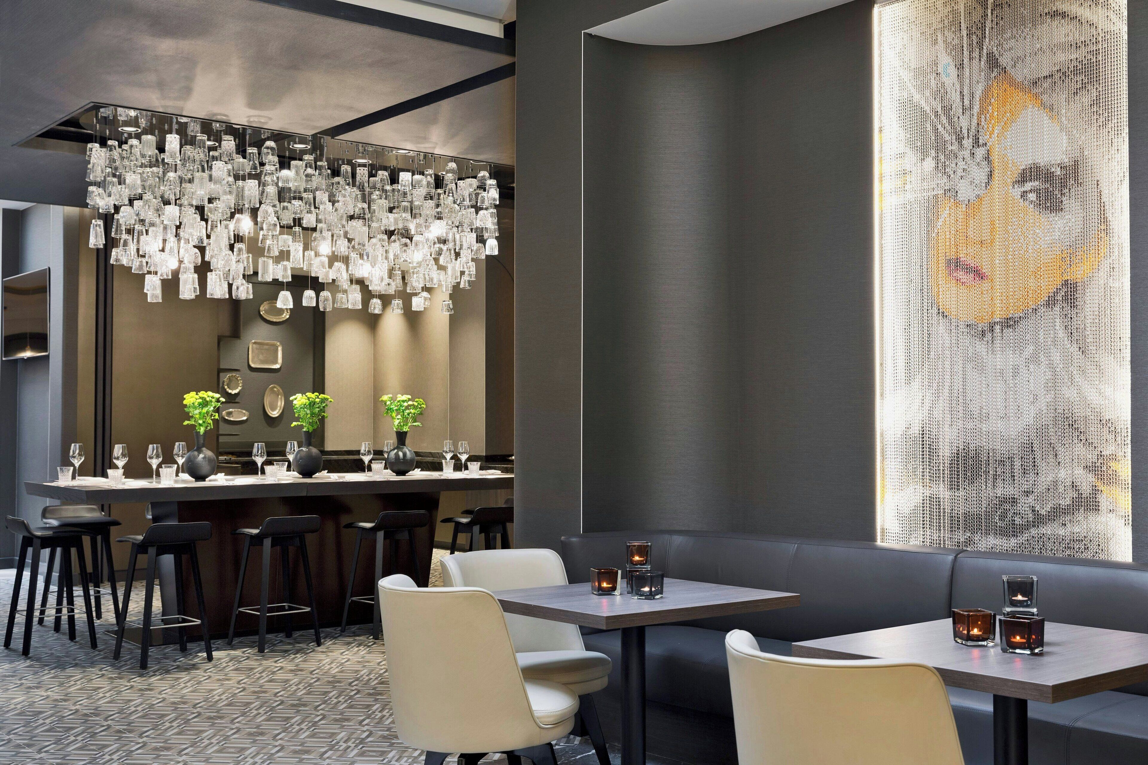 A modern restaurant interior with a bar area, seating, and a large decorative wall.