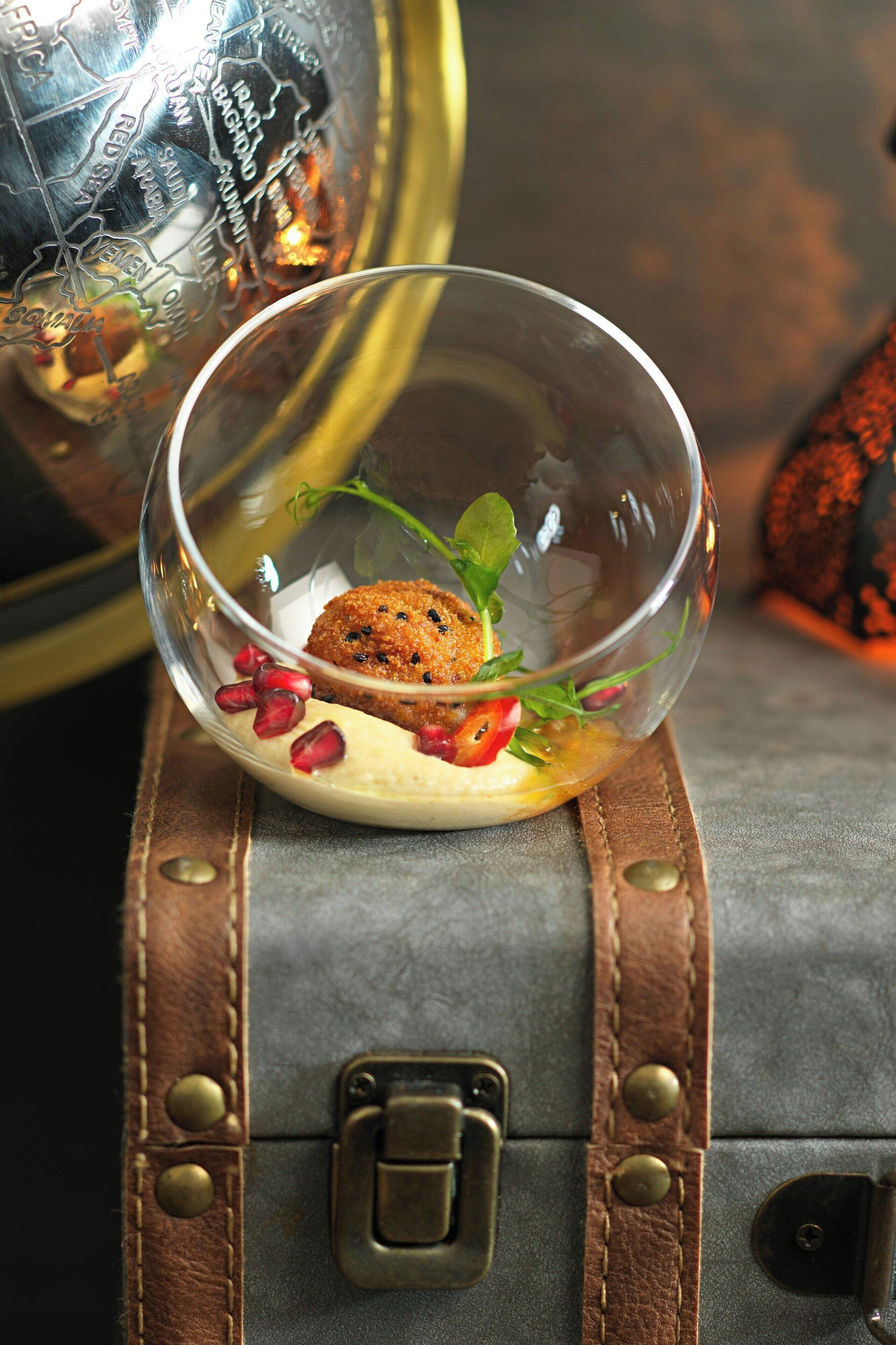 A dessert in a clear glass bowl on a leather strap.