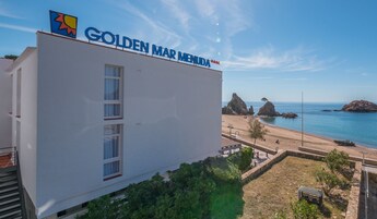 Hotel "Golden Mar Menuda", com vista para a praia e formações rochosas.