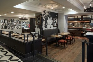 A restaurant with a bar area, seating, and a kitchen visible. - Kimpton Hotel Vintage Portland by IHG (Portland)