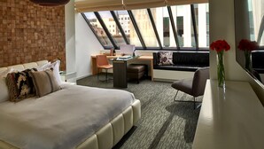 A modern hotel room with a large bed, a desk, a chair, and a view through the skylight. - Kimpton Hotel Vintage Portland by IHG (Portland)