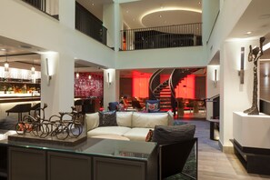 A spacious, multi-level interior with a central staircase, a bar area, and a seating arrangement. - Kimpton Hotel Vintage Portland by IHG (Portland)