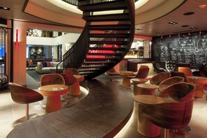 A modern interior with a spiral staircase, seating areas, and a bar with a chalkboard menu. - Kimpton Hotel Vintage Portland by IHG (Portland)