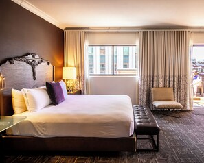 A hotel room with a large bed, a chair, a desk, and a window with curtains. - Kimpton Hotel Vintage Portland by IHG (Portland)