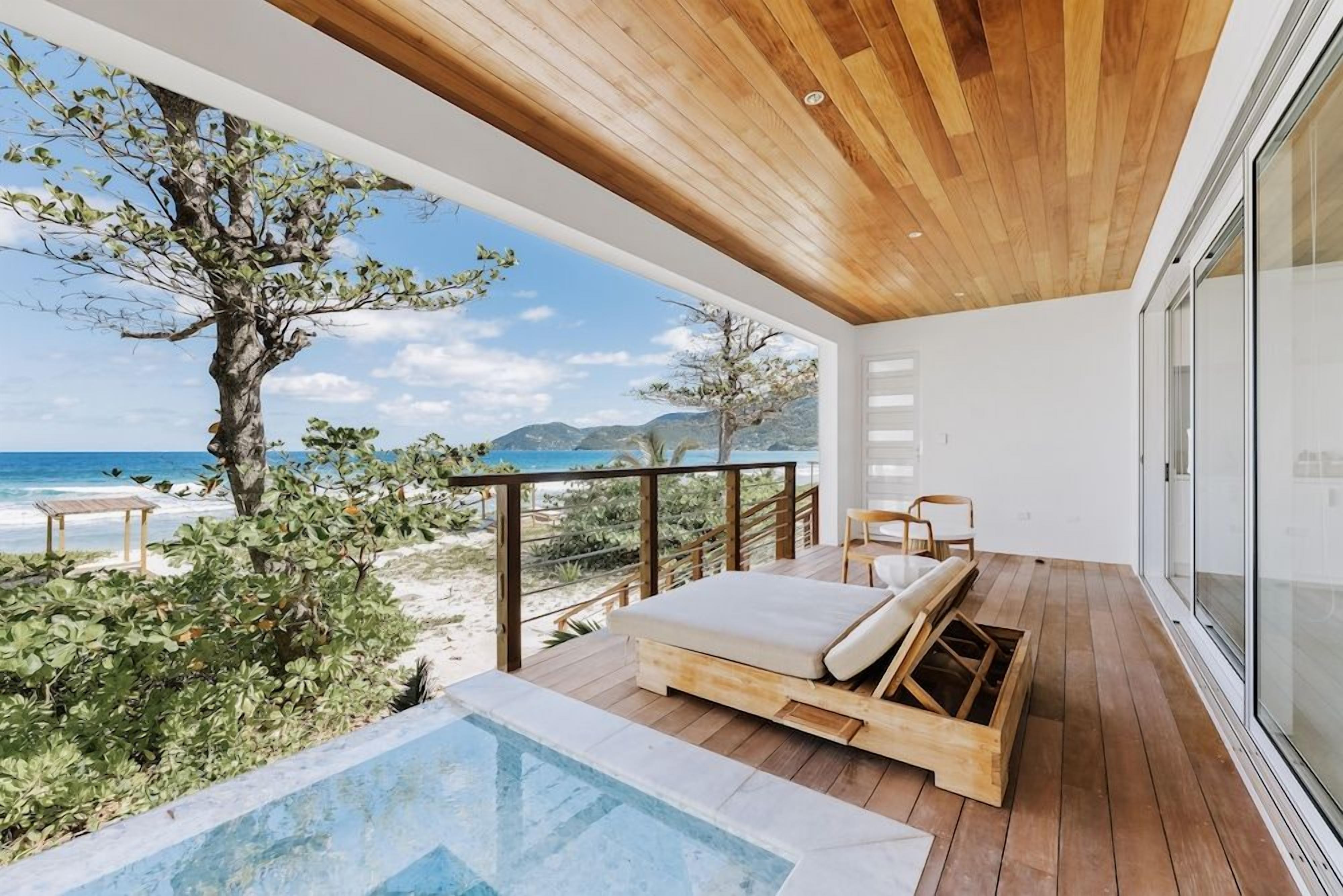 A wooden deck with a pool, lounge chairs, and a view of the ocean.