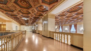 A grand hallway with ornate ceiling decorations, a wooden railing, and a long corridor. - Omni William Penn Hotel (Pittsburgh)