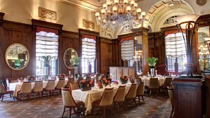 A formal dining room with multiple tables set for service, large chandeliers, and ornate wood paneling. - Omni William Penn Hotel (Pittsburgh)