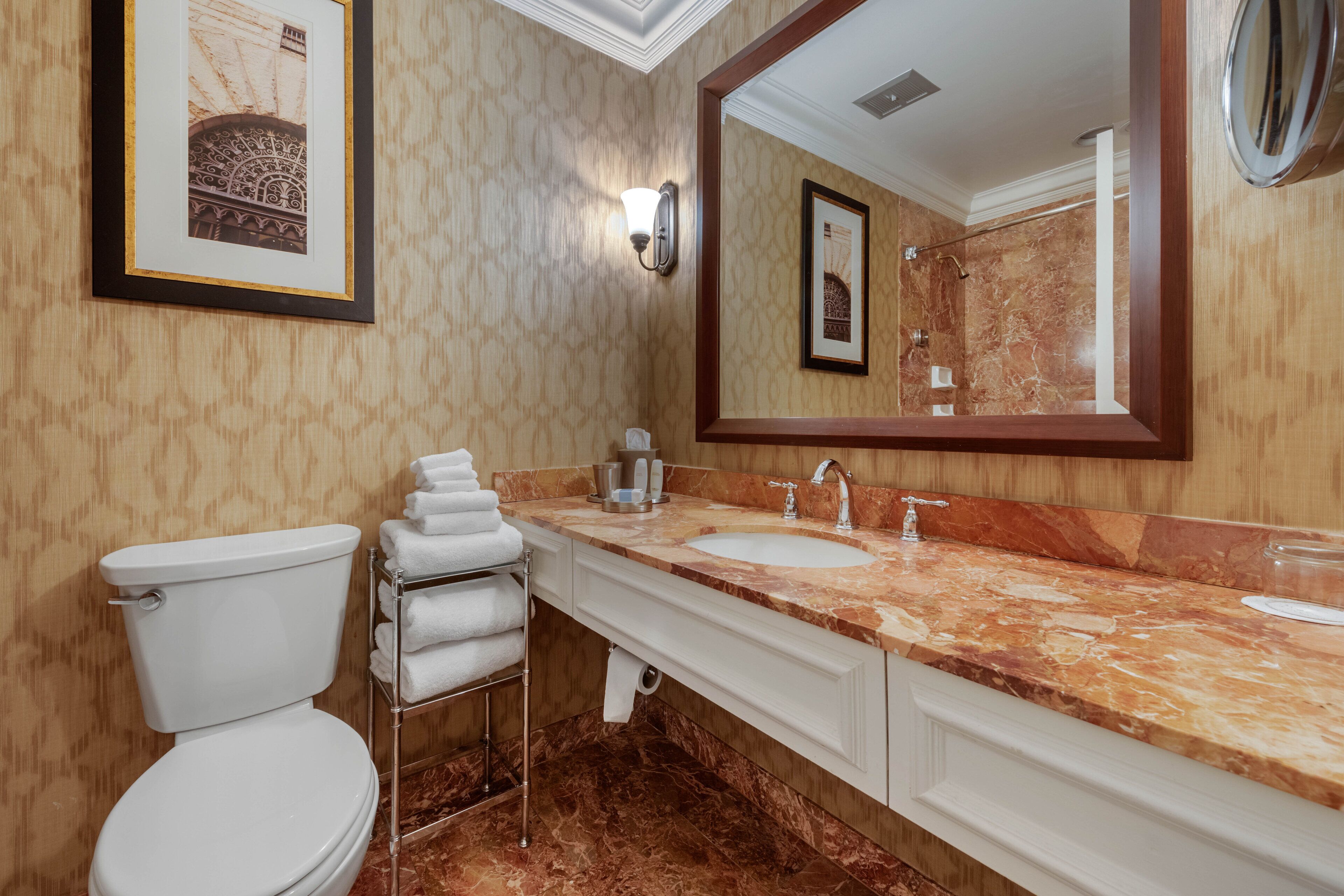A bathroom with a toilet, two sinks, a large mirror, and a towel rack.