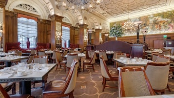 A spacious restaurant with high ceilings, ornate chandeliers, and a classic interior design.