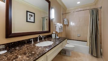 A bathroom with a marble sink, a large mirror, a toilet, and a bathtub.