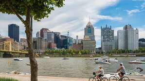 A river with boats and a city skyline in the background. - Omni William Penn Hotel (Pittsburgh)