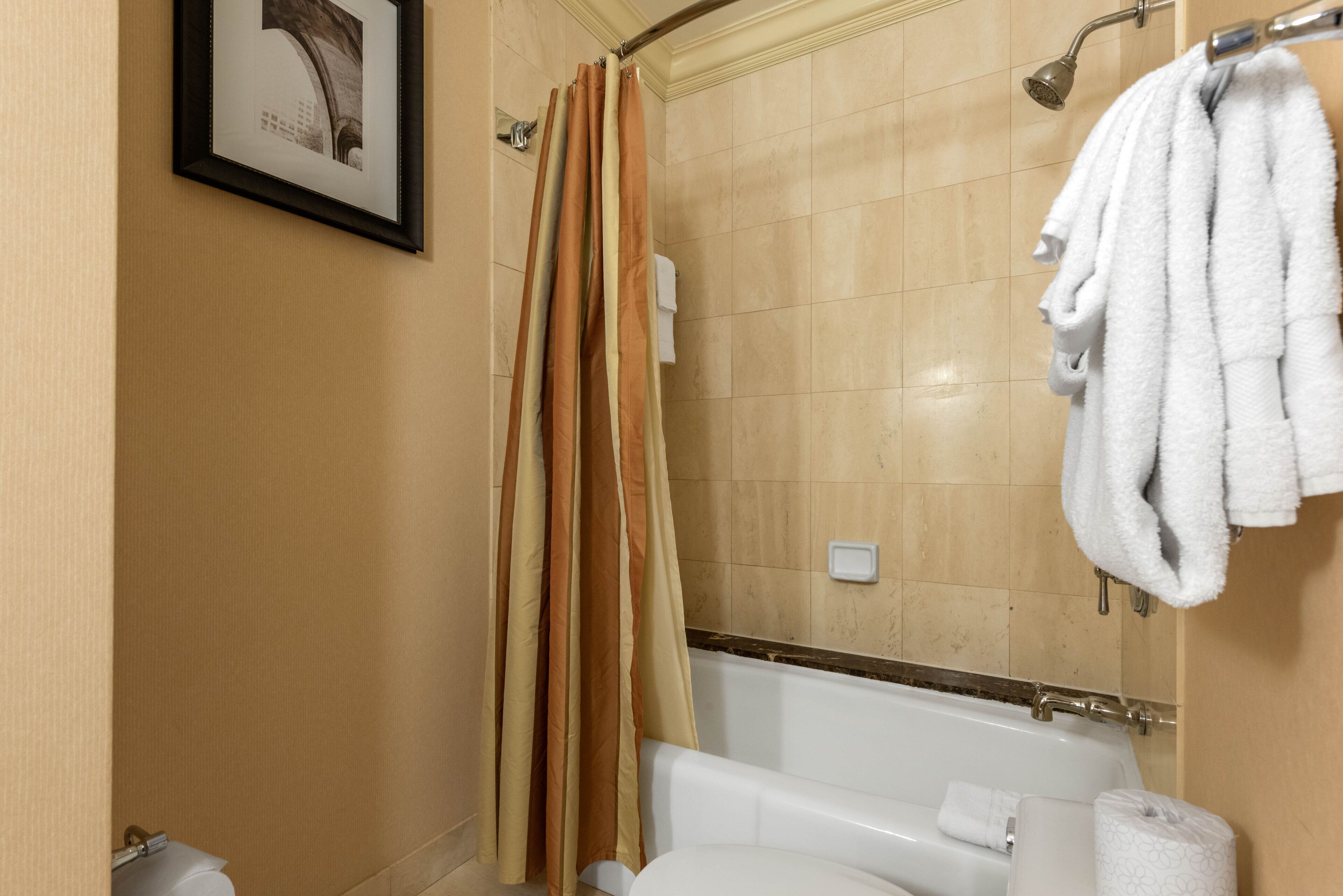 Ein Badezimmer mit einer Badewanne, einer Duschvorhang, einem Handtuchhalter und einer Toilette.