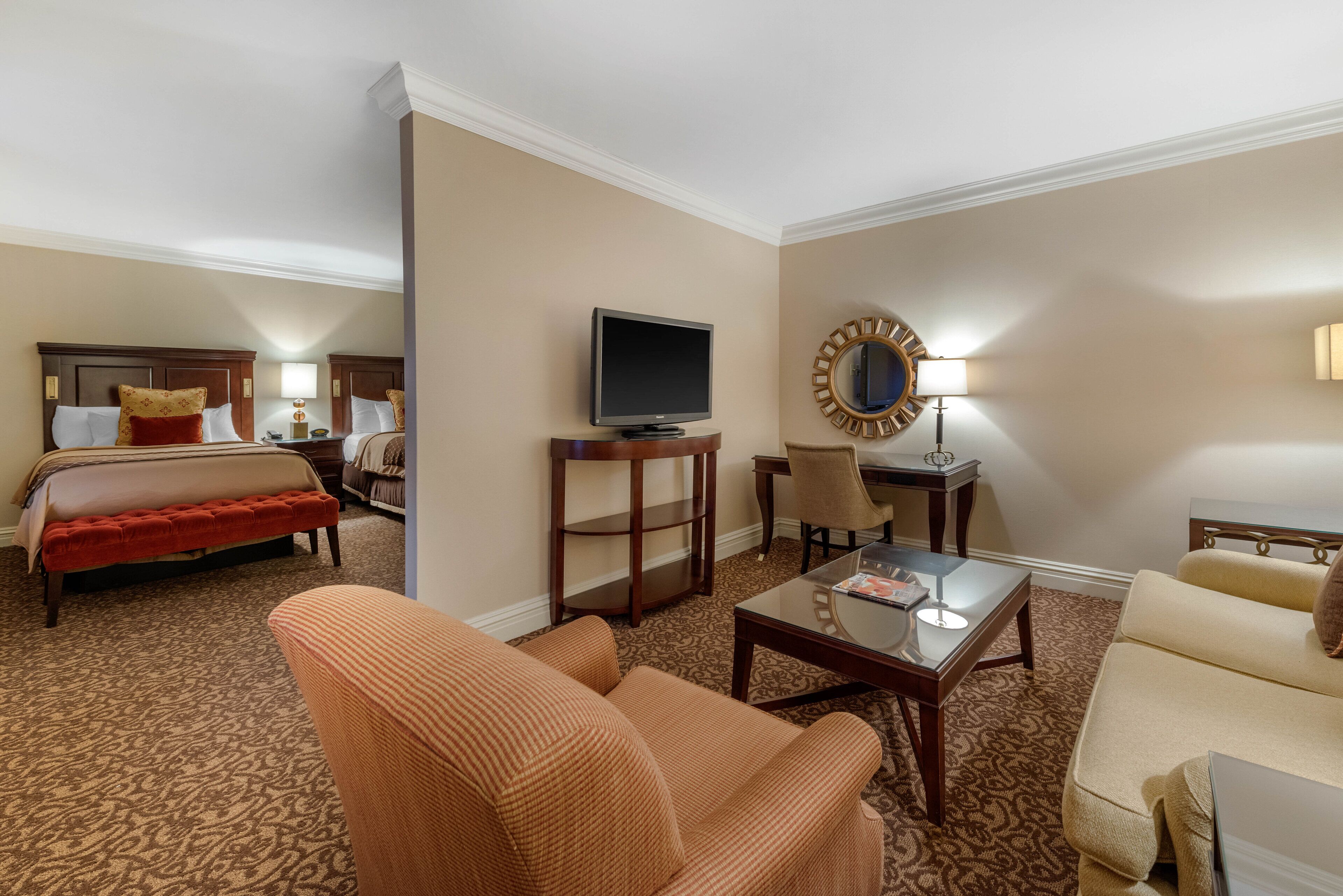 A hotel room with a bed, a TV, a sofa, a chair, and a small table.