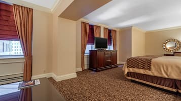 Una habitación de hotel con una cama grande, un televisor en un mueble de madera y una ventana con cortinas.