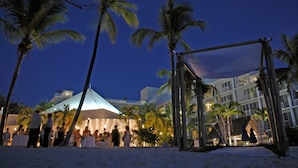 A beachside event with a tent and palm trees. - Grand Cayman Beach Suites (Seven Mile Beach)