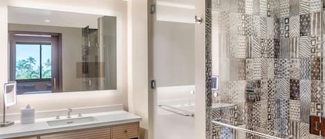 A modern bathroom with a large mirror, two sinks, and a shower area with patterned tiles.