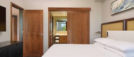 A bedroom with a large bed, wooden wardrobe, and a bathroom visible through an open door.