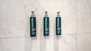 Three bottles of Crabtree shampoo and conditioner on a marble floor.