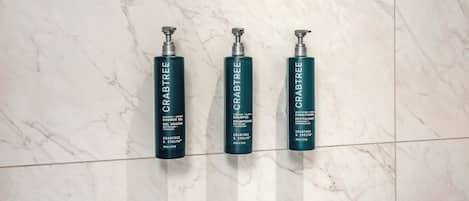 Three bottles of Crabtree shampoo and conditioner on a marble floor.