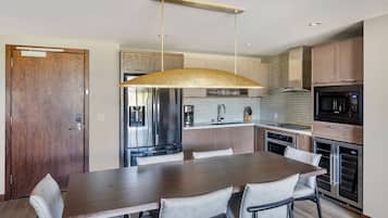 A modern kitchen with a wooden dining table, chairs, and stainless steel appliances.