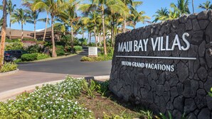 Un muro de piedra con el texto "MAUI BAY VILLAS" y "HILTON GRAND VACATIONS", indicando la ubicación de un hotel.